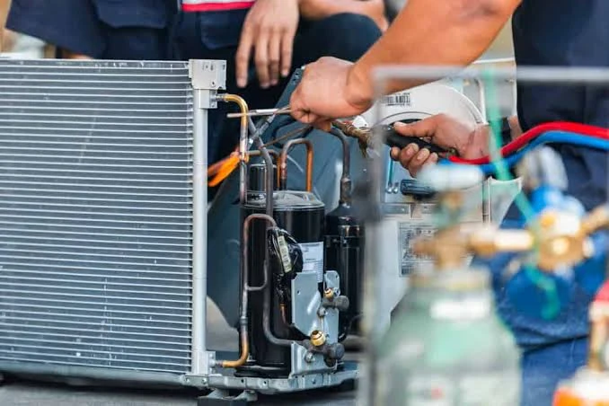Technician repairing the internal components and copper lines of an air conditioning unit