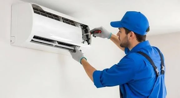 Technician repairing an open wall-mounted air conditioner with a screwdriver