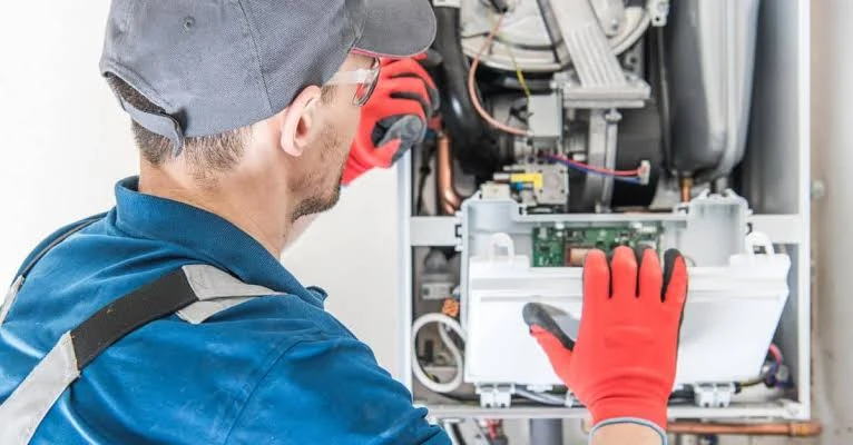 Technician inspecting the controls inside a wall-mounted heating system